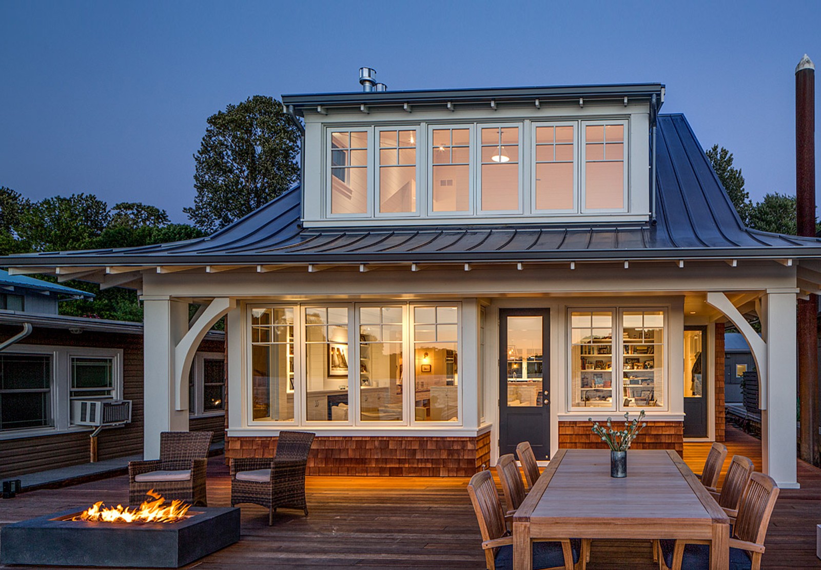 Exterior image of a house with lots of windows and lights on inside as the sun is setting